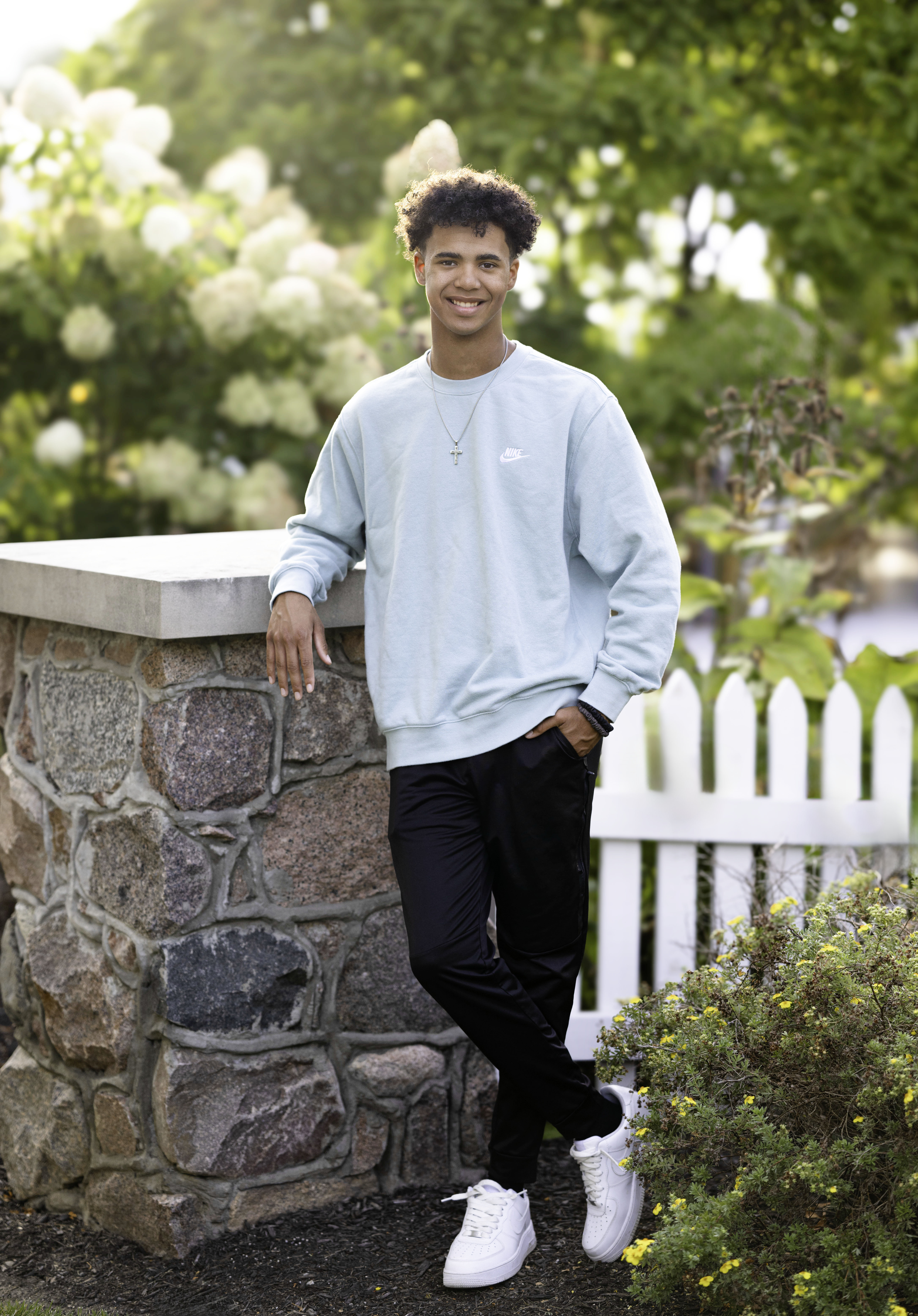 Male high school senior leaning on brick pillar